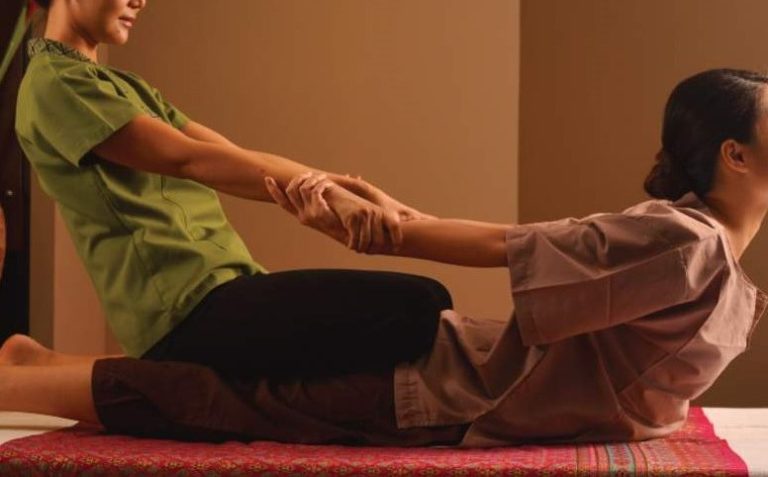 Eine Person erhält eine traditionelle Thai-Massage von einer Therapeutin.